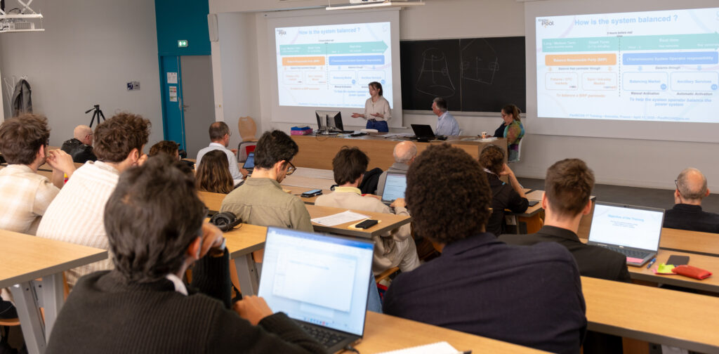 Consortium members attending the FlexRICAN training session in a hybrid format at G2Elab, seated around a conference table with a presentation screen in the background.